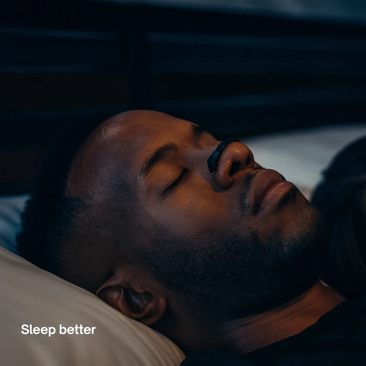 Man sleeping using AirMag pro Nasal Strip with 'Sleep better' text in a dark setting