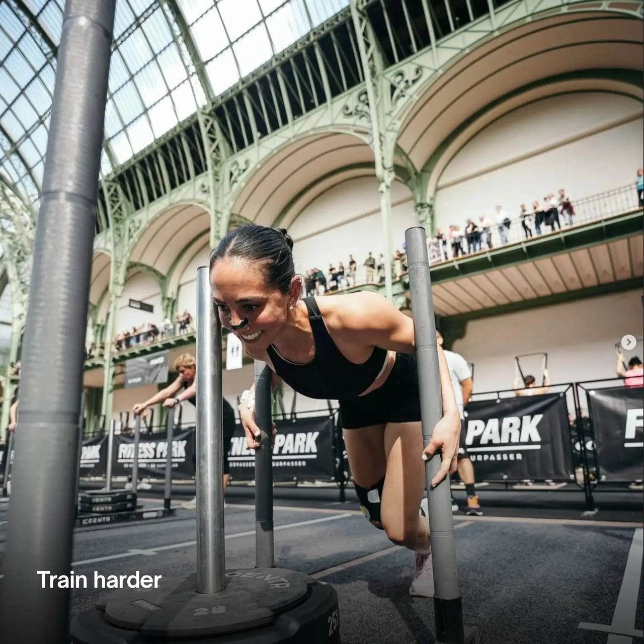 Woman participating in an obstacle course event in a large indoor arena with AirMag Pro Nasal Strips